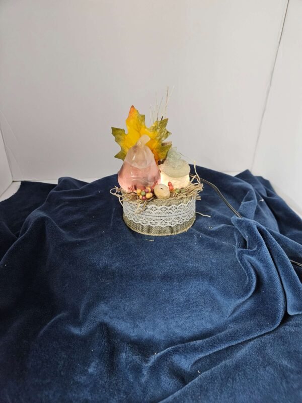 Two fluorite pumpkins with fall leaves on a lighted stand