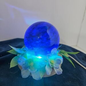 Four-inch blue glass sphere with flowers on a lighted stand