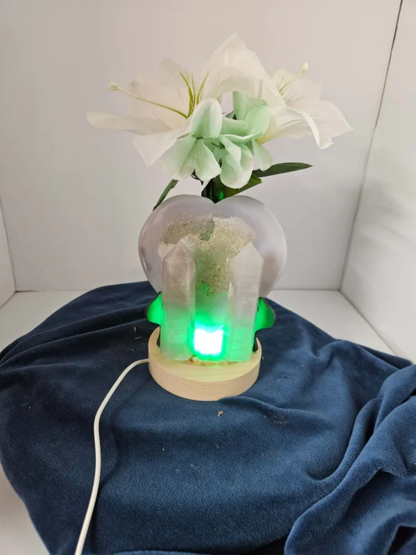Two agate towers and one druzy agate heart slab on a lighted stand with flowers