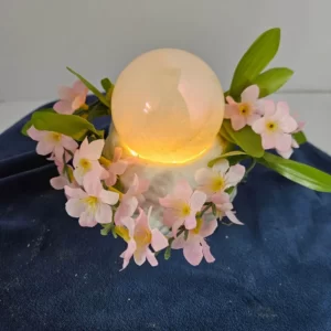 Two-inch calcite sphere with flowers on a ceramic stand with fairy lights