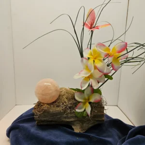 Rose quartz sphere on driftwood with flowers