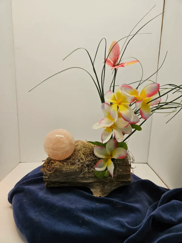 Rose quartz sphere on driftwood with flowers